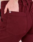 Mid-Rise Work Pants in Red Wine close up of Margaret's hand in the back pocket