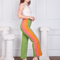 Side view of Hand-Painted Stripe Western Pants in Bright Olive and vintage off-white Tank Top worn by Alex. Pink and orange hand painted stripe down the side of the pant leg.