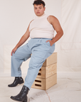 Miguel is wearing Heavyweight Trousers in Periwinkle and vintage off-white Sleeveless Tank Top. He is sitting on a stack of wooden crates.