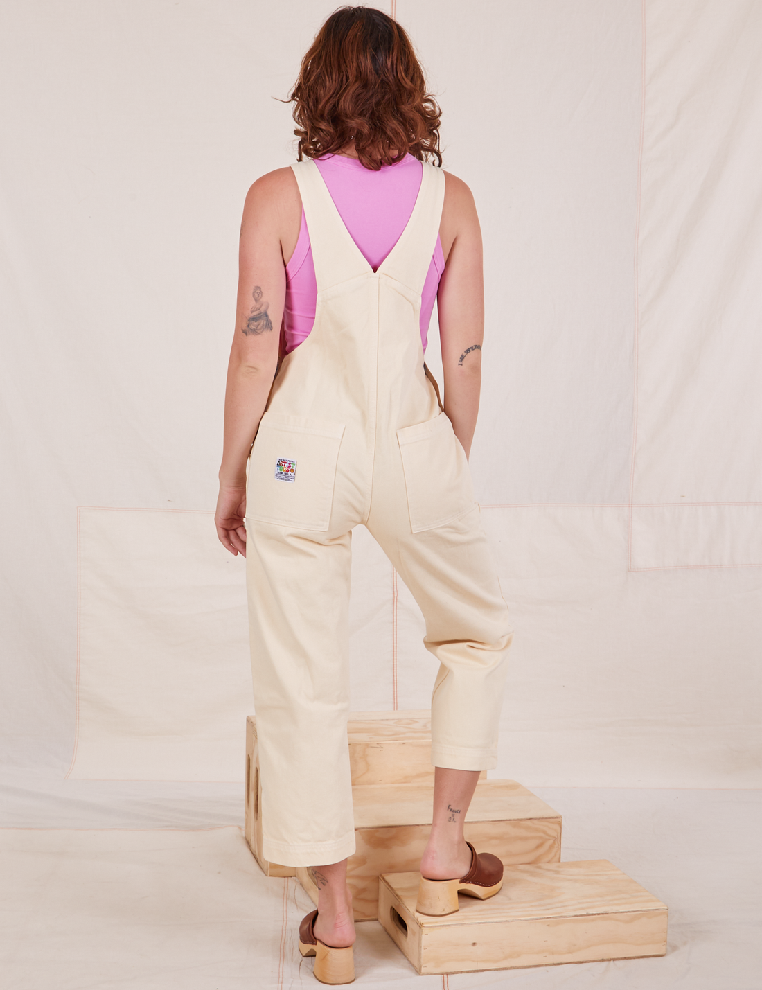 Back view of Rainbow Overalls and bubblegum pink Cropped Tank Top underneath worn by Alex