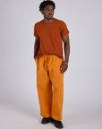 Isaac is 5’10” and wearing M Drop Pocket Cargo Pants in Creamsicle Orange paired with a burnt terracotta Organic Vintage Tee