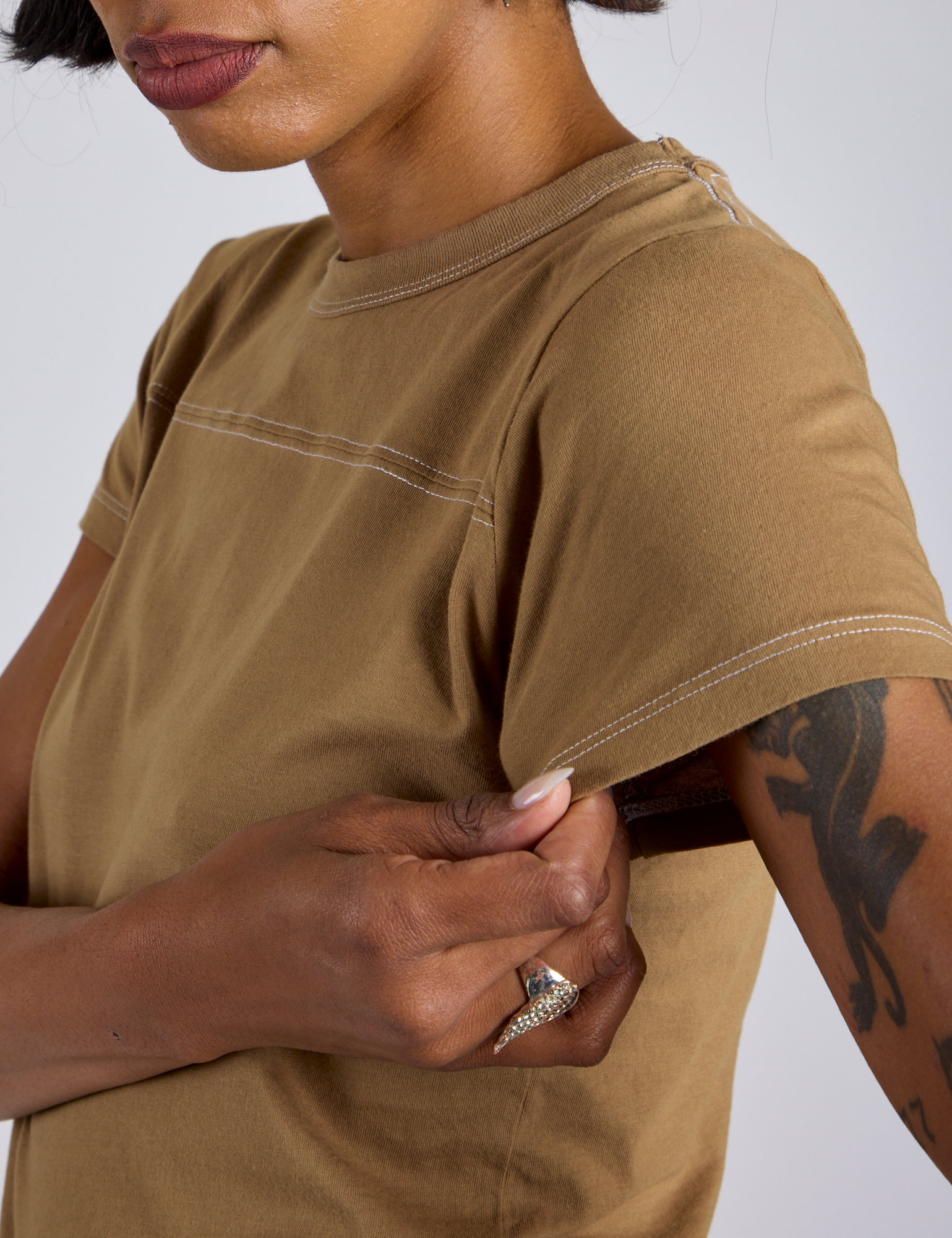 Close up of Jr. Varsity Tee in Desert Brown sleeve on Kira