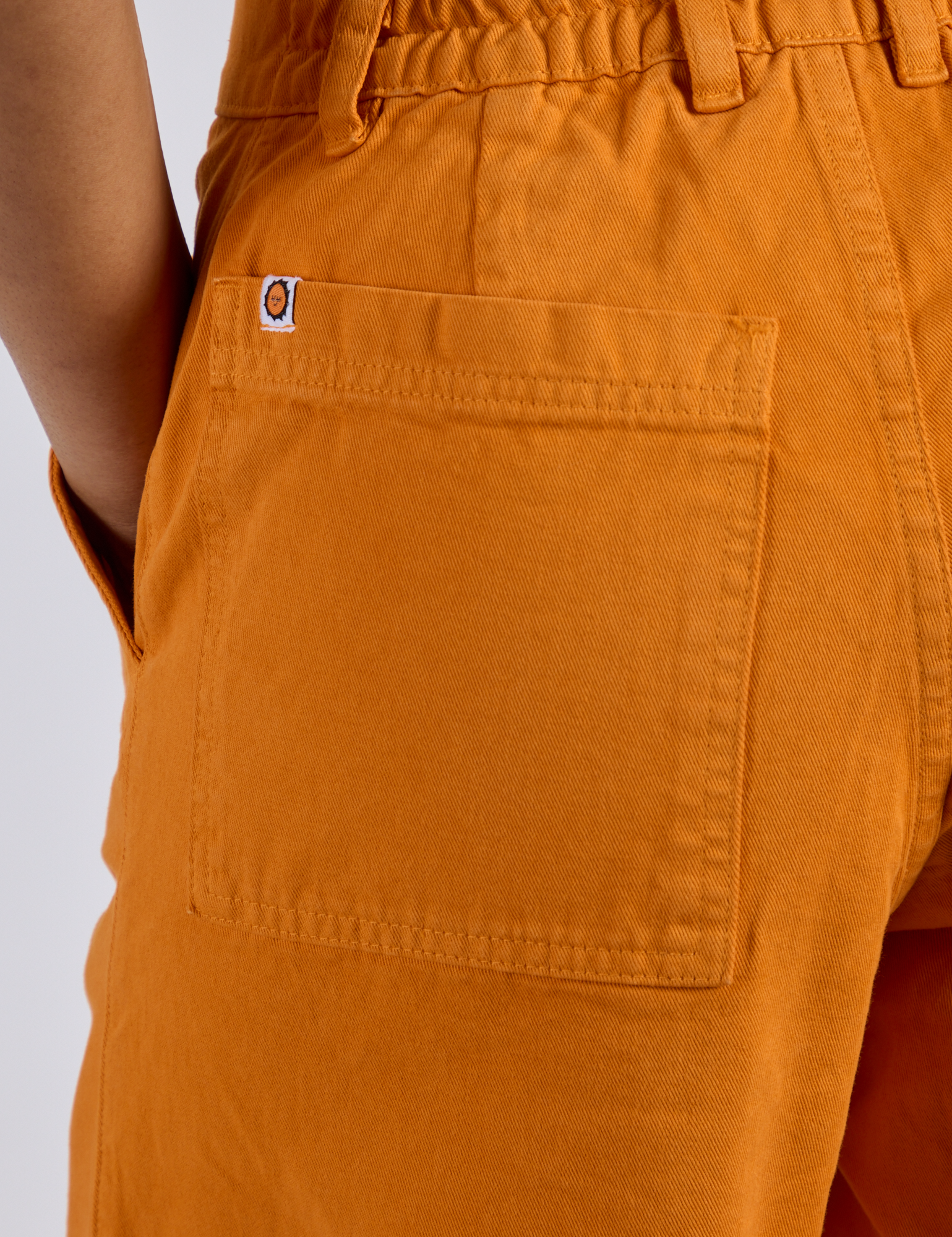 Close up of Longline Work Shorts in Creamsicle Orange back pocket on Kira