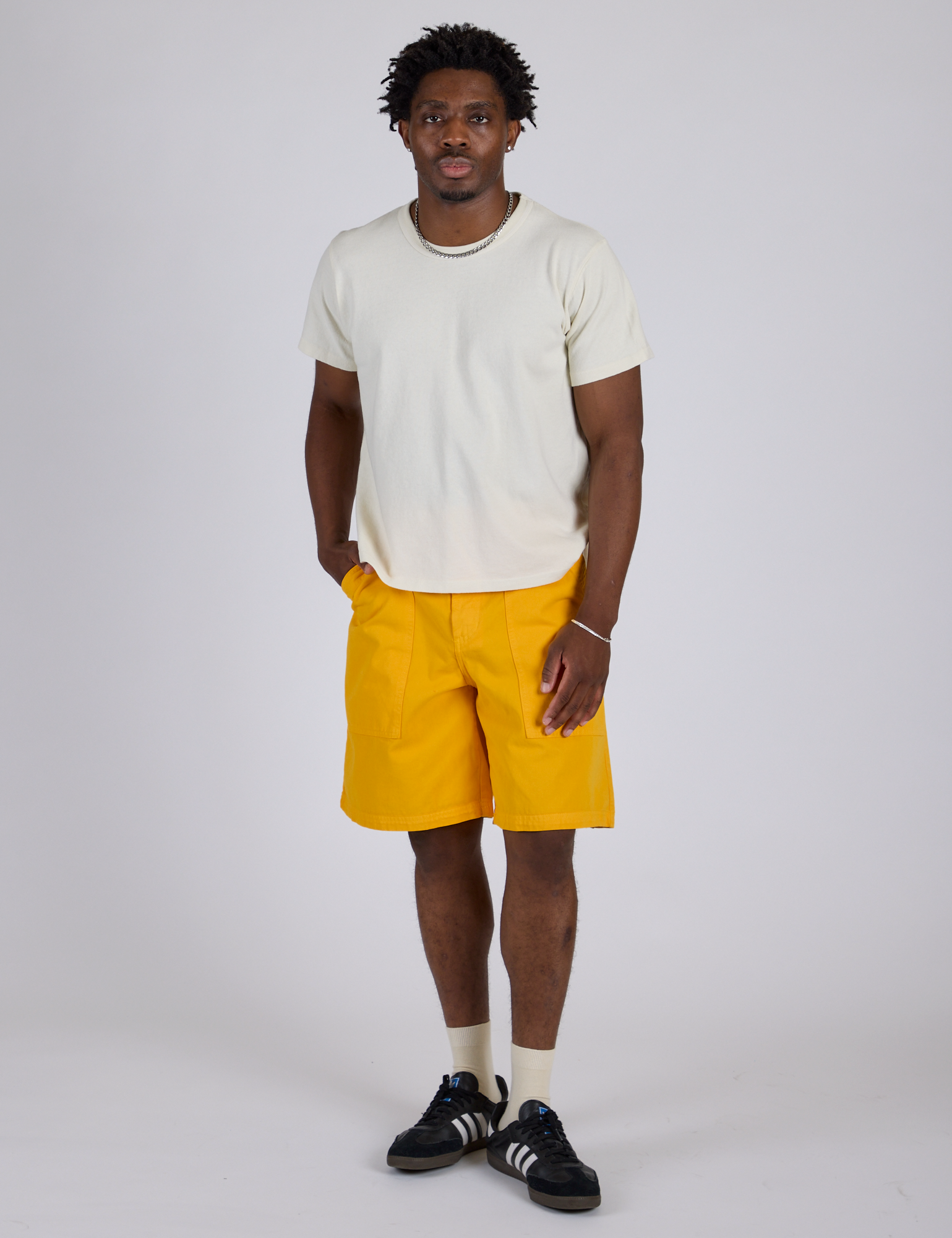 Isaac is 5’10” and wearing M Longline Work Shorts in Sunshine Yellow paired with Burly Tee in Vintage Tee White