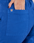 Work Pants in Royal Blue back pocket close up with Tiara's hand in the pocket.