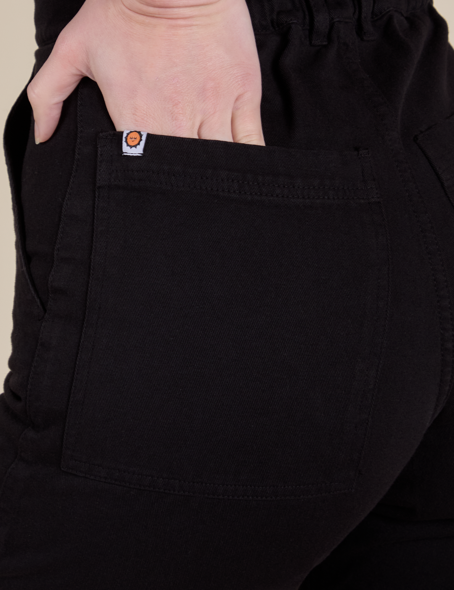 Close up of Alex's hand in the back pocket of Short Sleeve Jumpsuit in Basic Black
