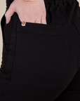 Close up of Alex's hand in the back pocket of Short Sleeve Jumpsuit in Basic Black