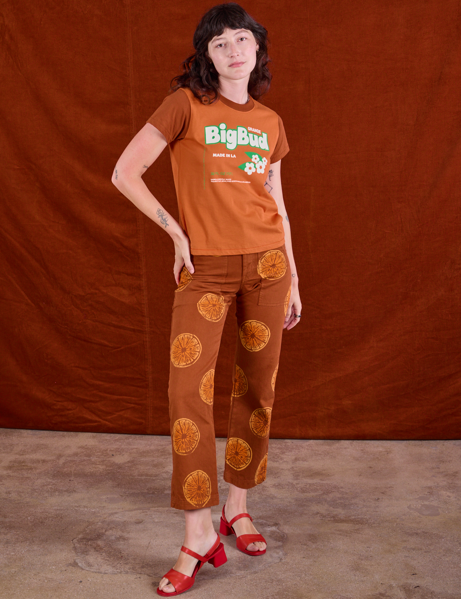 Alex is 5’8” and wearing P Vintage Tee in Orange Soda paired with Paintstamped Work Pants in Orange