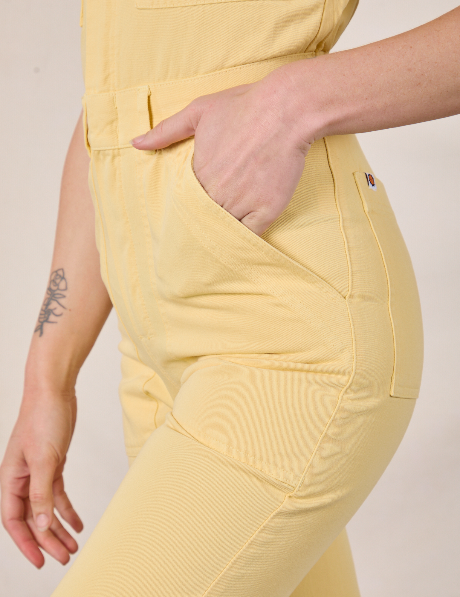 Side close up of Alex&#39;s hand in the pocket of Short Sleeve Jumpsuit in Butter Yellow