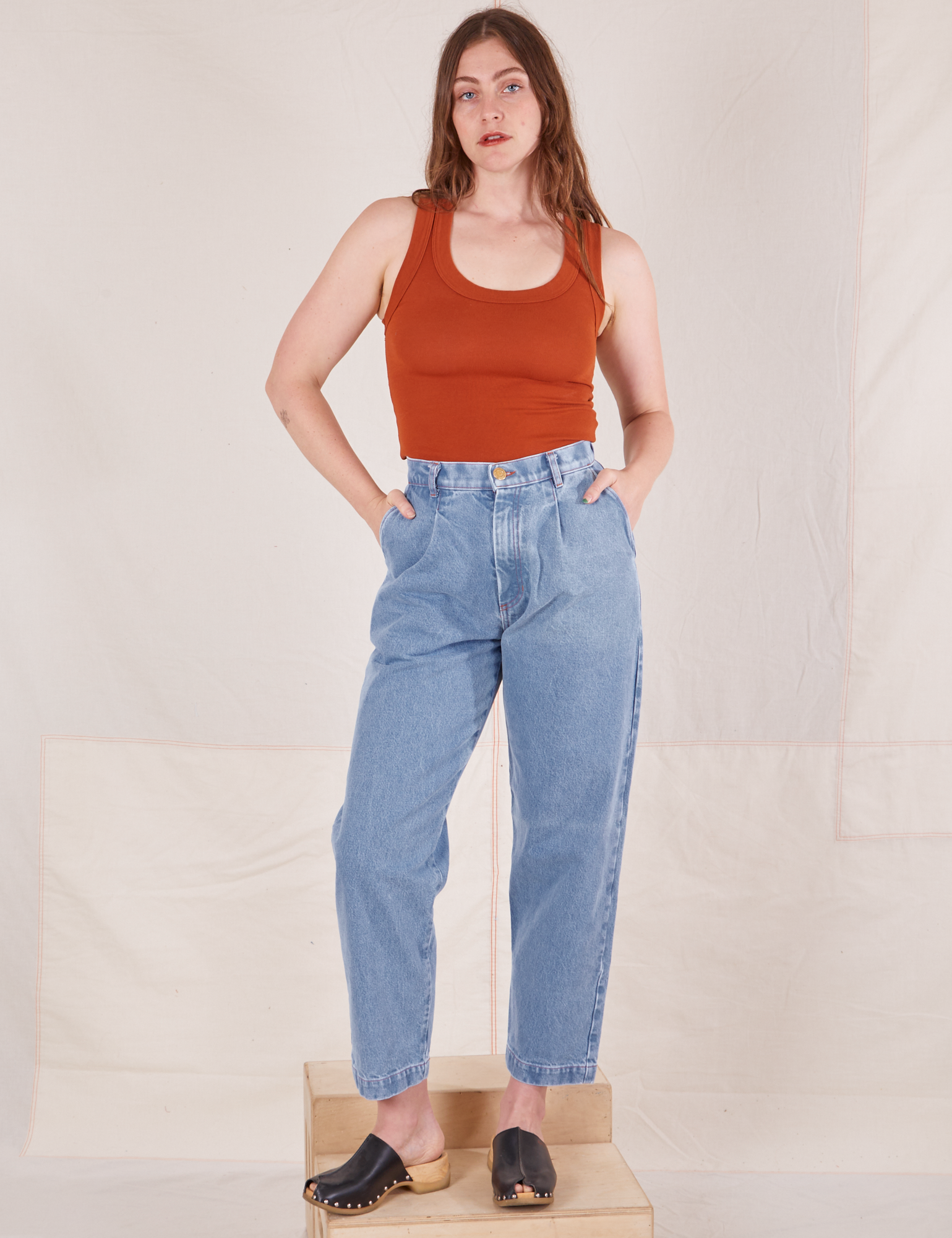 Allison is 5&#39;10&quot; and wearing XS Denim Trouser Jeans in Light Wash paired with a burnt orange Tank Top