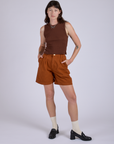 Alex is 5’8” and wearing XXS Pleated Trouser Shorts in Burnt Terracotta paired with fudgesicle brown Muscle Tee