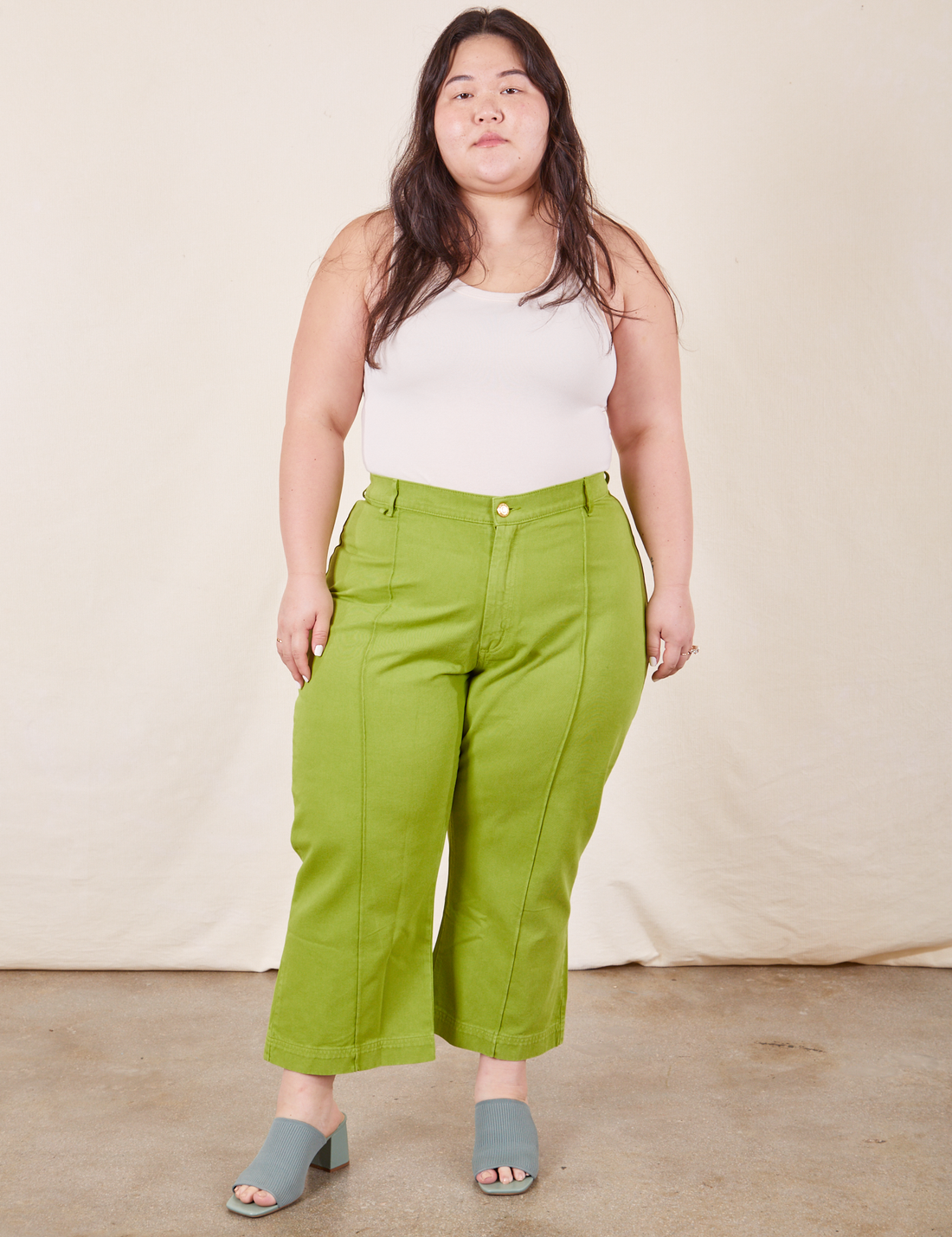 Ashley is 5'7 and wearing 1XL Petite Western Pants in Gross Green paired with a vintage-off white Tank Top