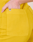 Close up of Alex's hand in the back pocket of Western Pants in Golden Yellow