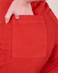 Close up of Alex's hand in the back pocket of Western Pants in Mustang Red