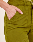 Front pocket close up of Work Pants in Olive Green. Worn by Soraya with her hand in the pocket.