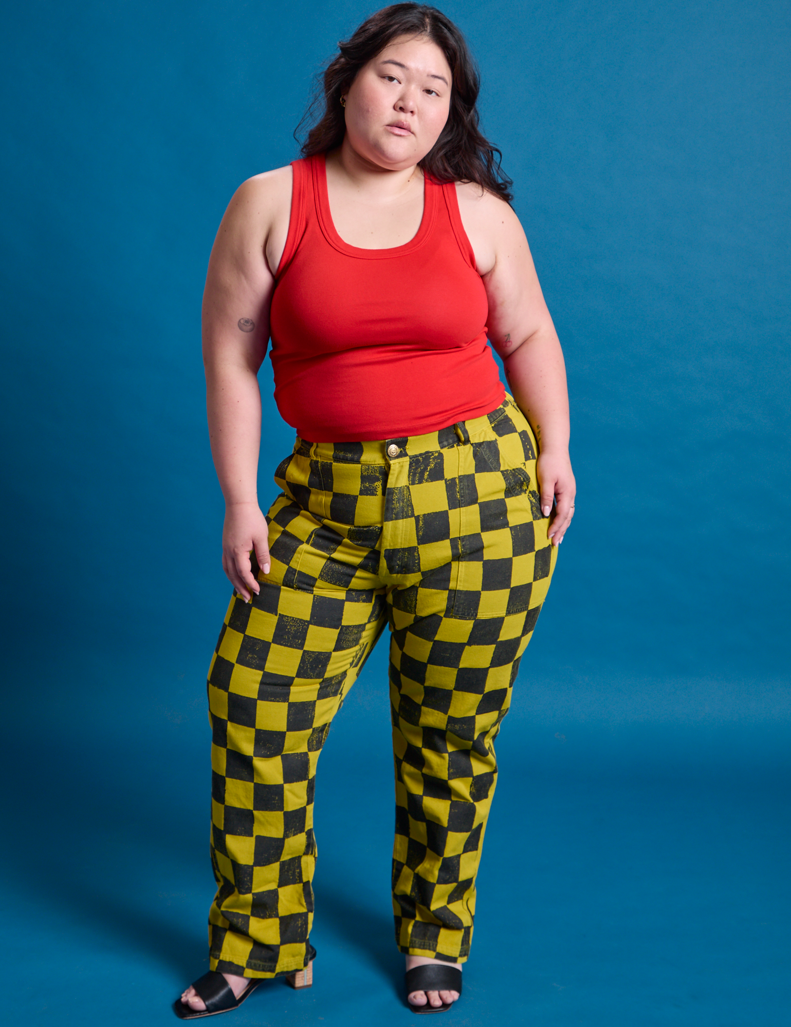 Ashley is 5&#39;7&quot; and wearing 1XL Checkerboard Work Pants in Yellow/Black paired with a mustang red Tank Top