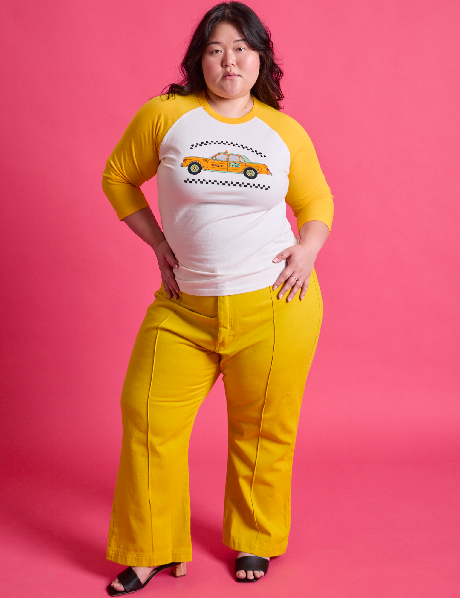 Ashley is wearing Taxi Raglan Tee in Toronto paired with golden yellow Western Pants