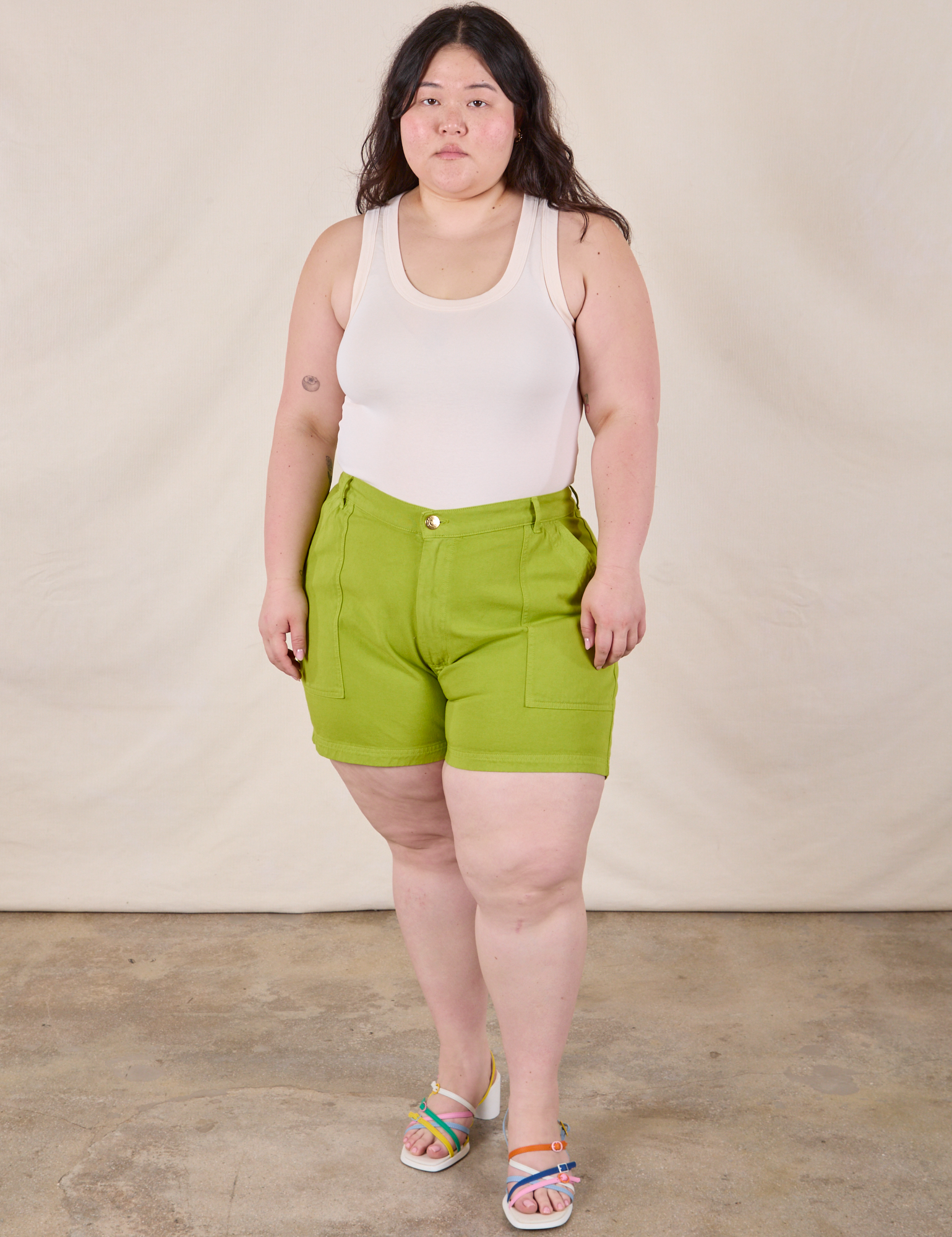 Ashley is 5’7” and wearing 1XL Classic Work Shorts in Gross Green paired with a Tank Top in Vintage Tee Off-White