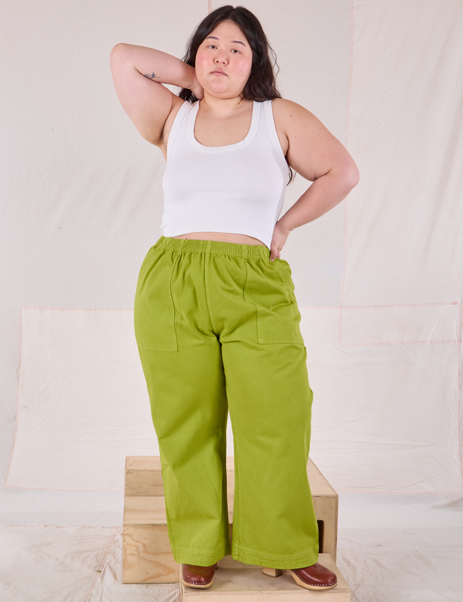 Ashley is 5&#39;7&quot; and wearing 1XL Action Pants in Gross Green paired with a Cropped Tank in Vintage Tee Off-White