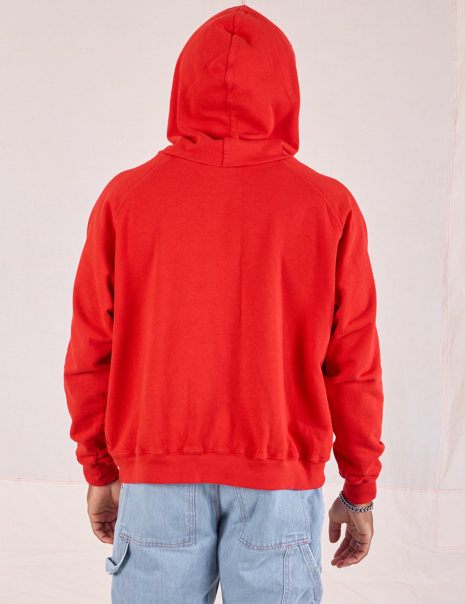 Back view of Collegiate Hoodie in Mustang Red with hood worn over head on Issac