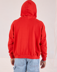 Back view of Collegiate Hoodie in Mustang Red with hood worn over head on Issac