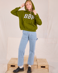 Margaret is wearing Collegiate Hoodie in Summer Olive paired with light wash Carpenter Jeans