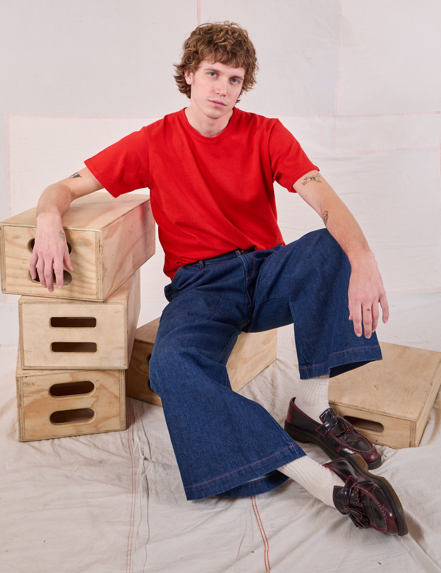 Quinn is wearing Burly Tee in Mustang Red and dark wash Wide Leg Denim Trousers