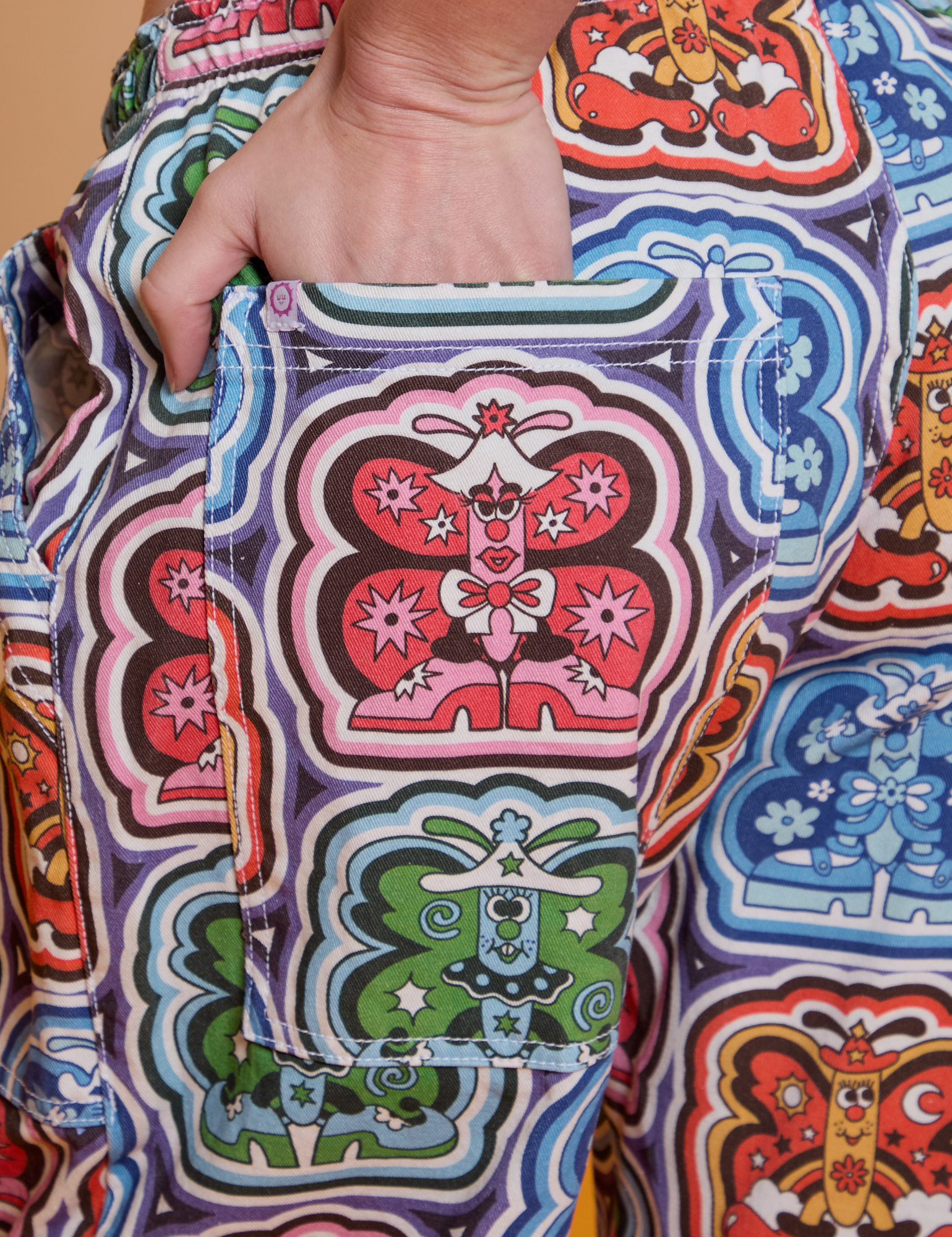 Close up of Alex's hand in the back pocket of Butterfly Kaleidoscope Drop Pocket Cargo Pants