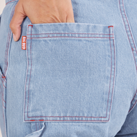 Back pocket close up of Carpenter Jeans in Light Wash. Tiara has her hand tucked into the pocket.