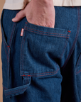 Close up of Quinn's hand in the back pocket of Carpenter Jeans in Dark Wash