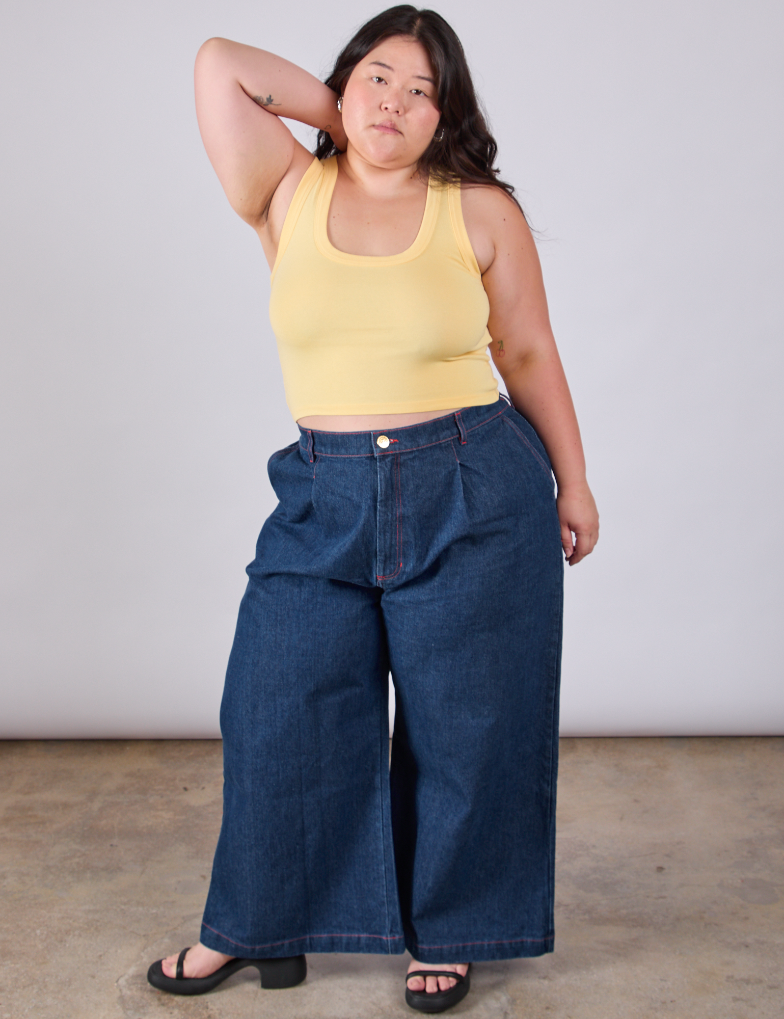 Ashley is wearing Cropped Tank Top in Butter Yellow paired with dark wash Indigo Wide Leg Trousers