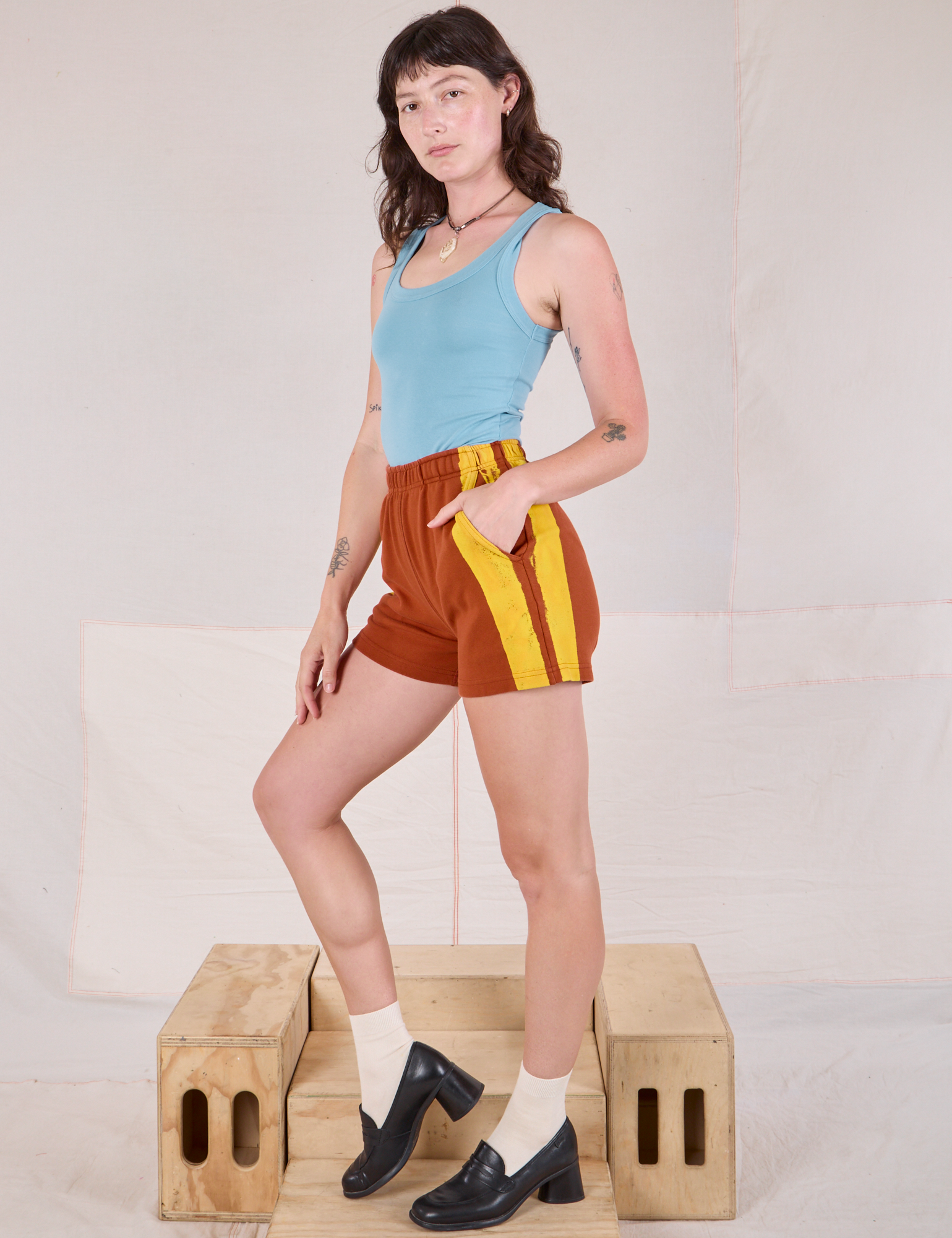 Side view of Painted Stripe Easy Shorts in Burnt Terracotta and baby blue Tank Top on Alex