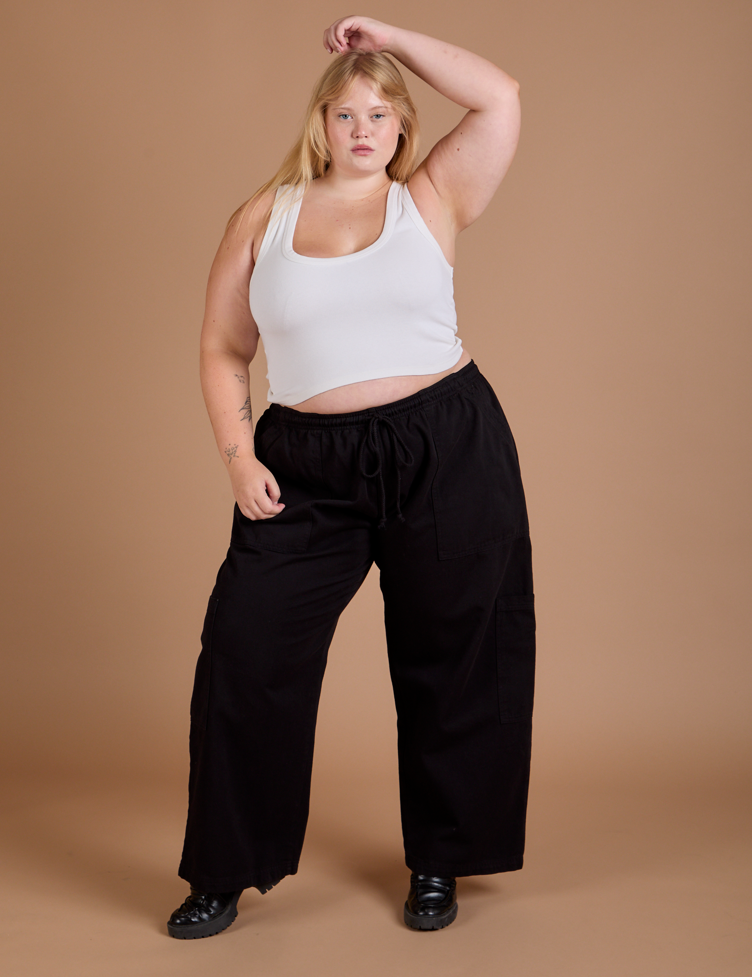 Juliet is 5’7” and wearing 1XL Drop Pocket Cargo Pants in Basic Black paired with a Cropped Tank in vintage tee white