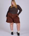 Juliet is 5’7” and wearing 2XL Pleated Trouser Shorts in Fudgesicle Brown paired with espresso brown Long Sleeve Baby Tee