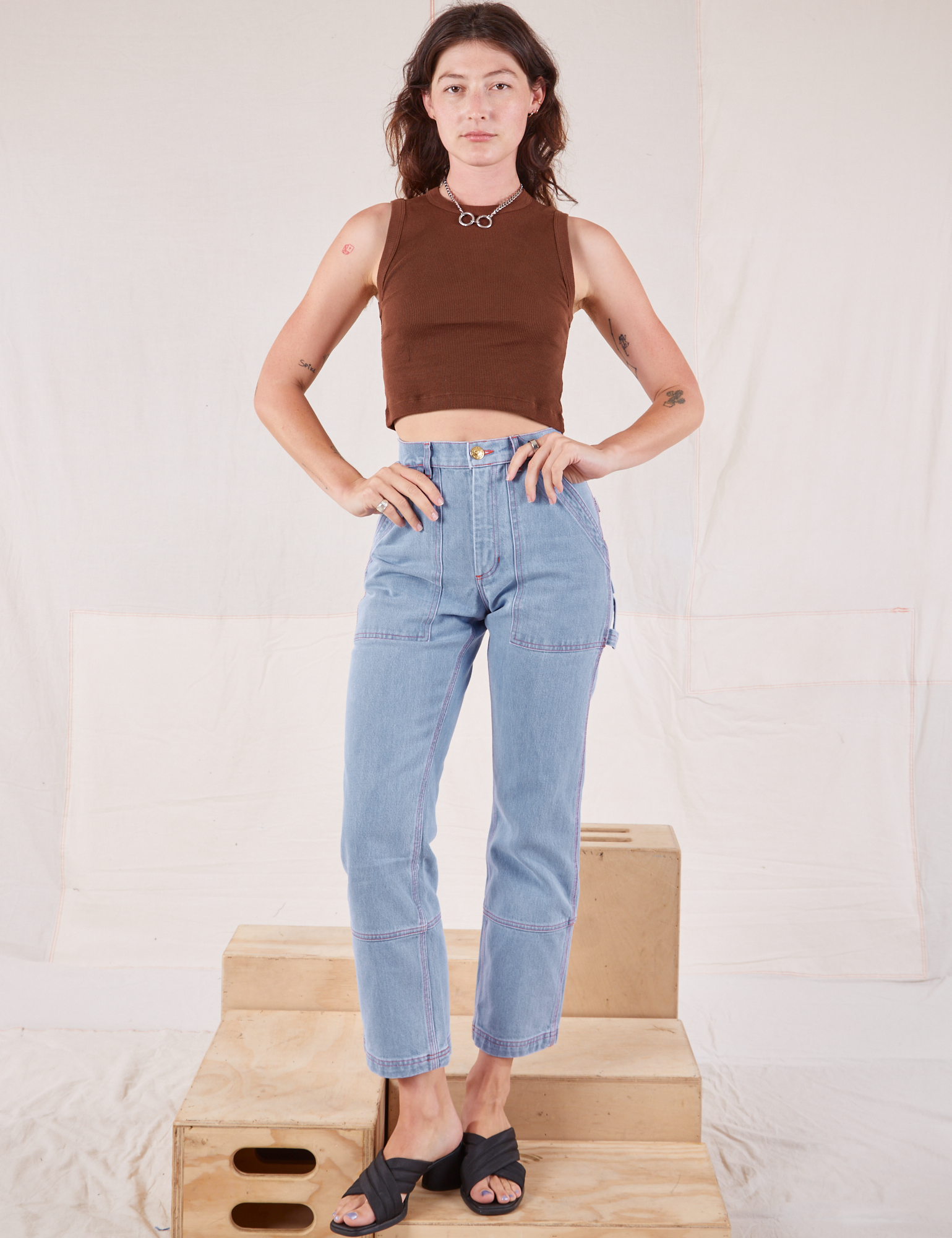 Alex is wearing Muscle Tee in Fudgesicle Brown and light wash Carpenter Jeans