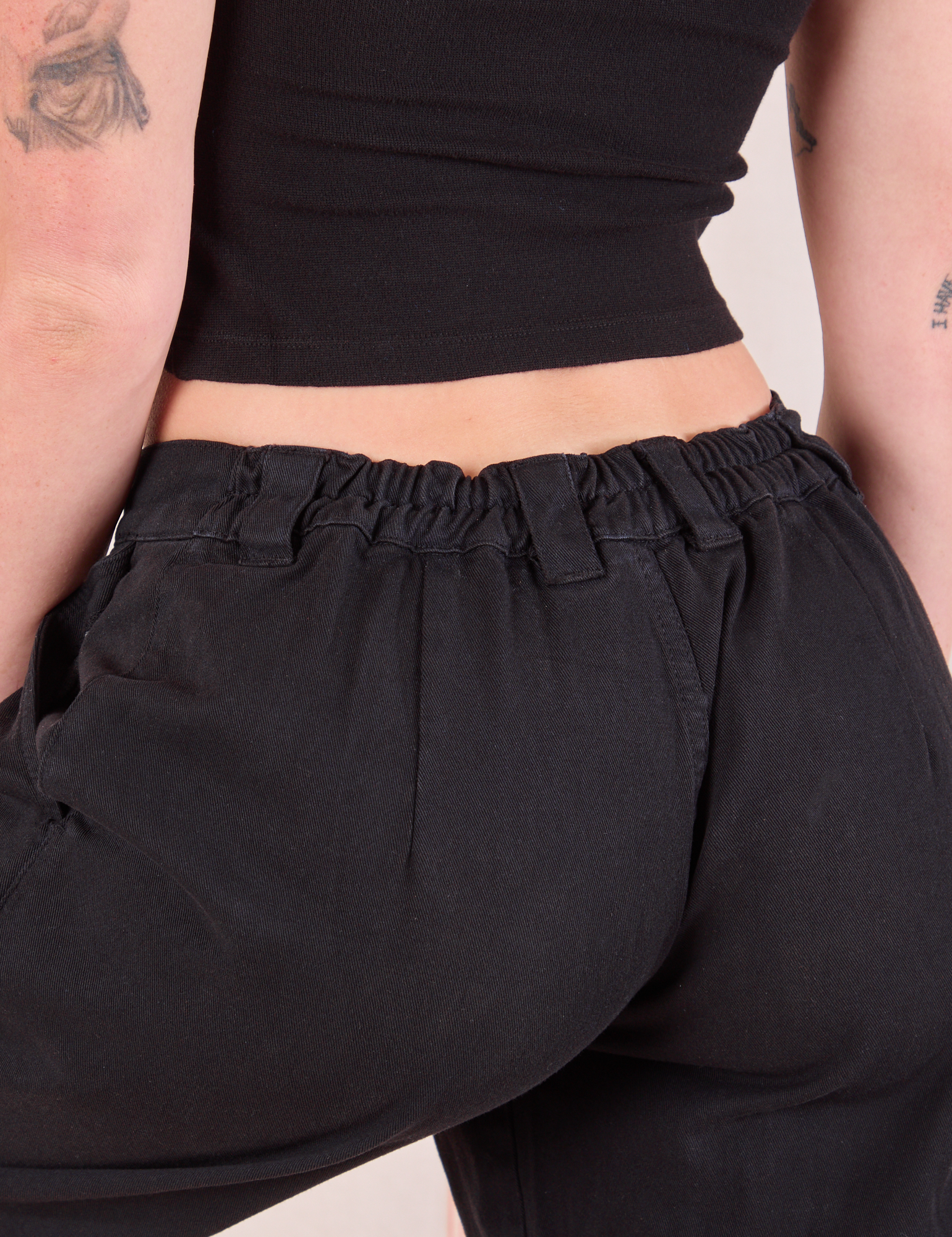 Mid-Rise Pleated Trousers in Basic Black back view close up on Alex