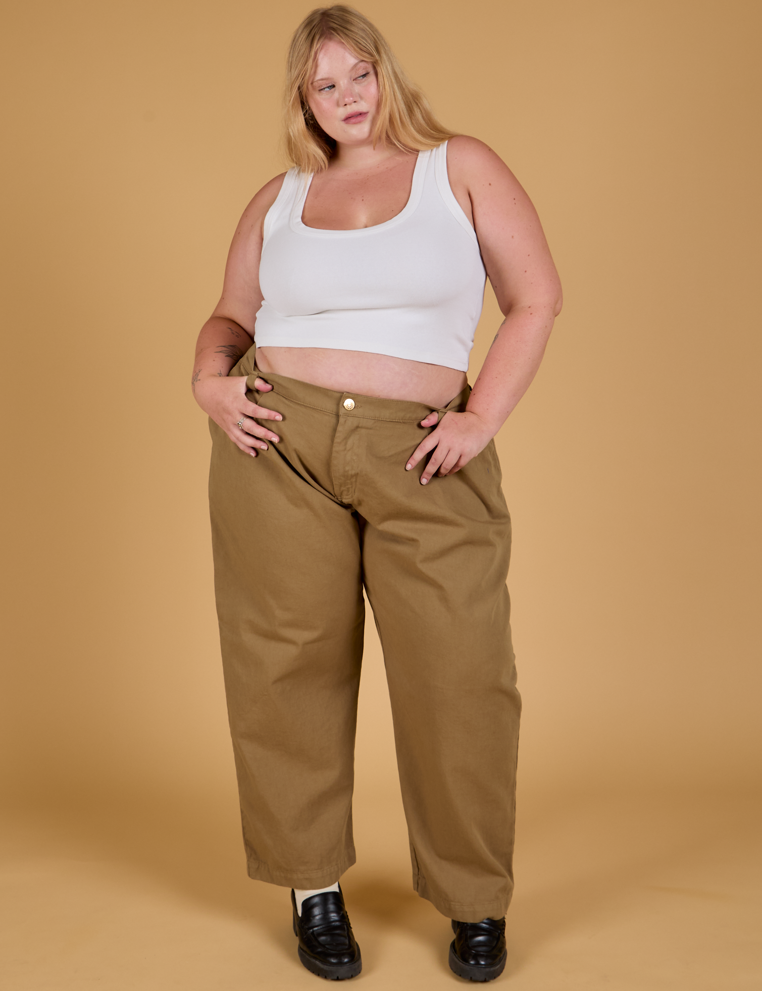 Juliet is 5&#39;7&quot; and wearing 1XL Baggy Mid-Rise Trousers in Desert Brown paired with a vintage tee white Cropped Tank