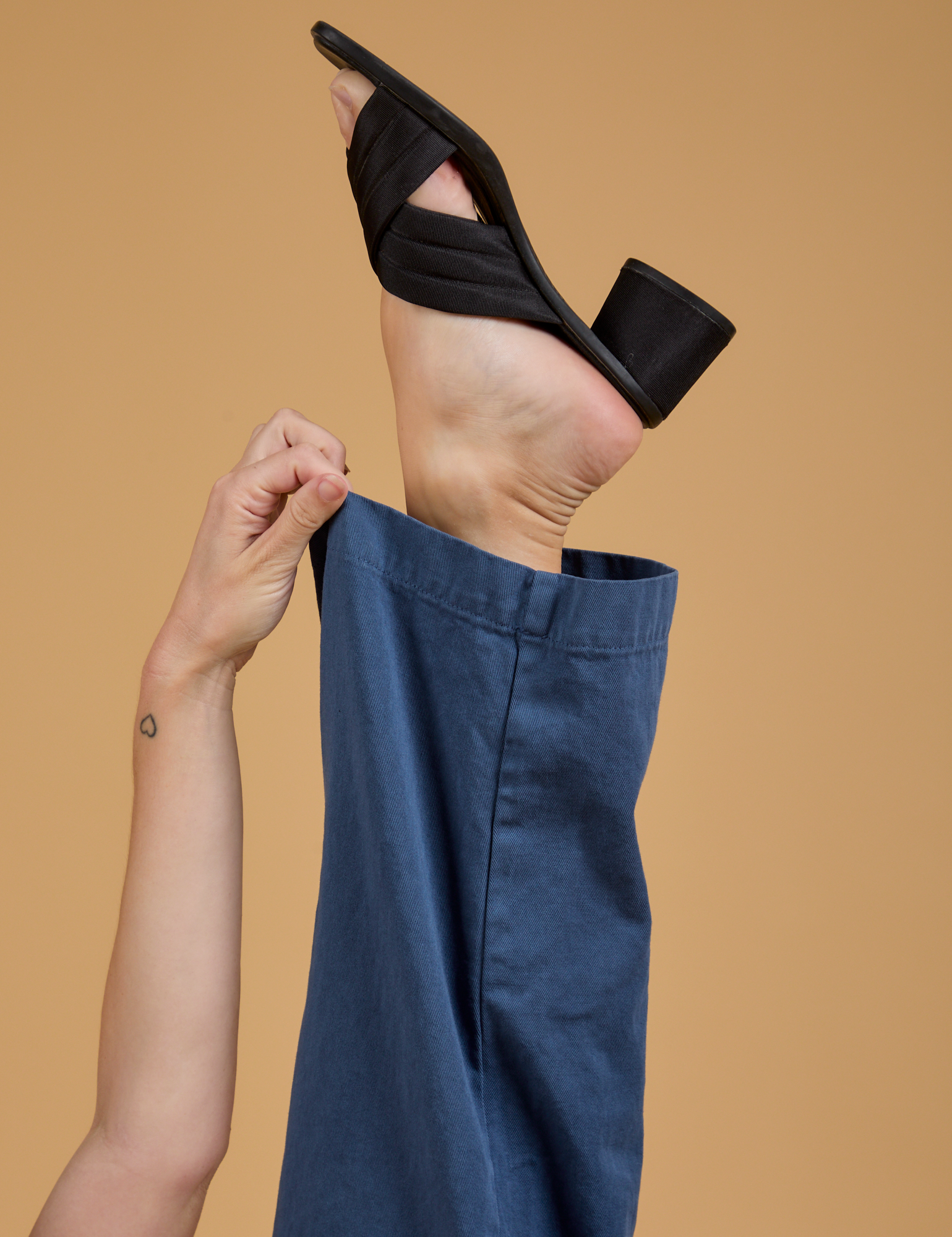 Alex is pulling on the hem of the Baggy Mid-Rise Trousers in French Blue