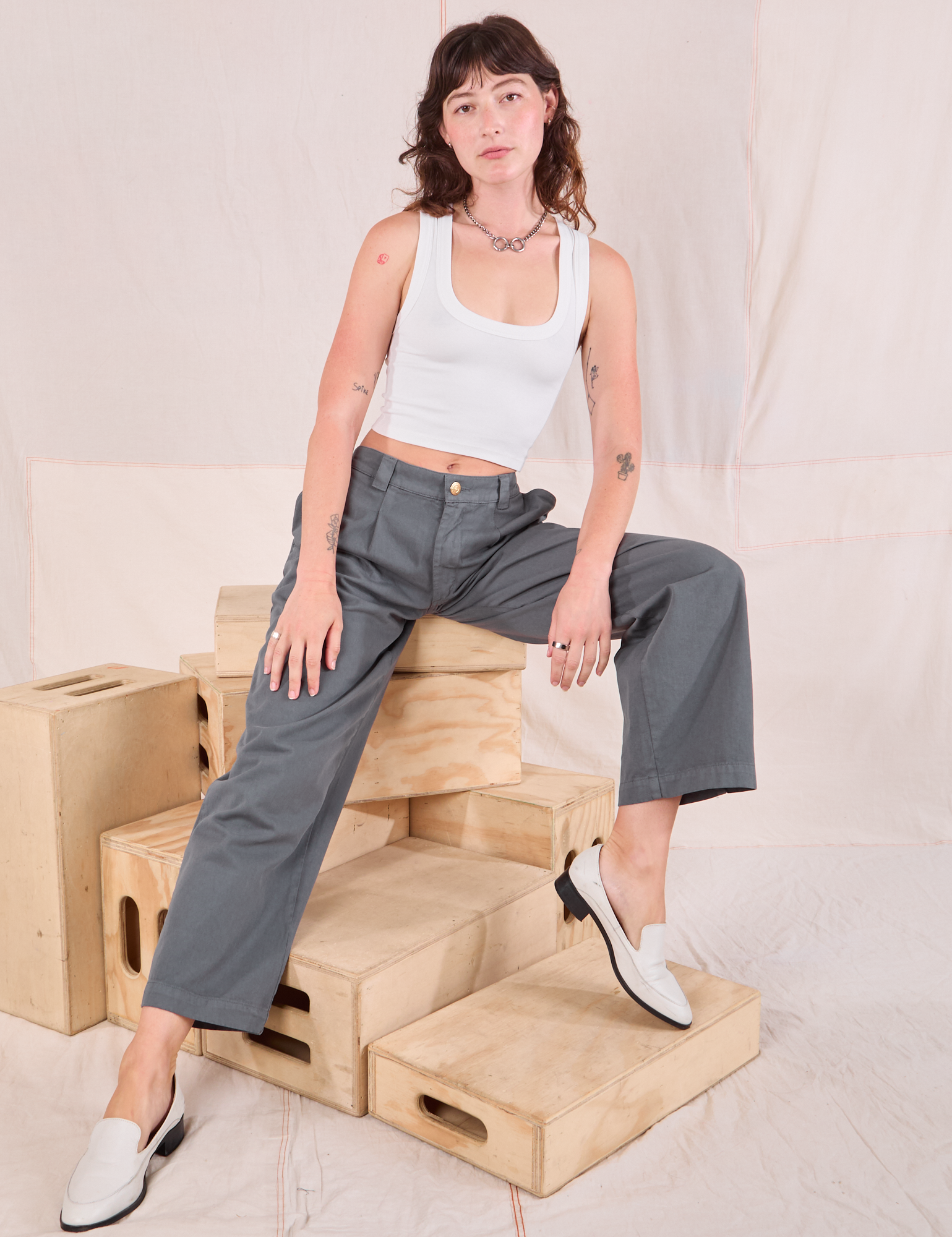 Alex is wearing Mid-Rise Pleated Trousers in Slate Grey and Cropped Tank in vintage tee off-white