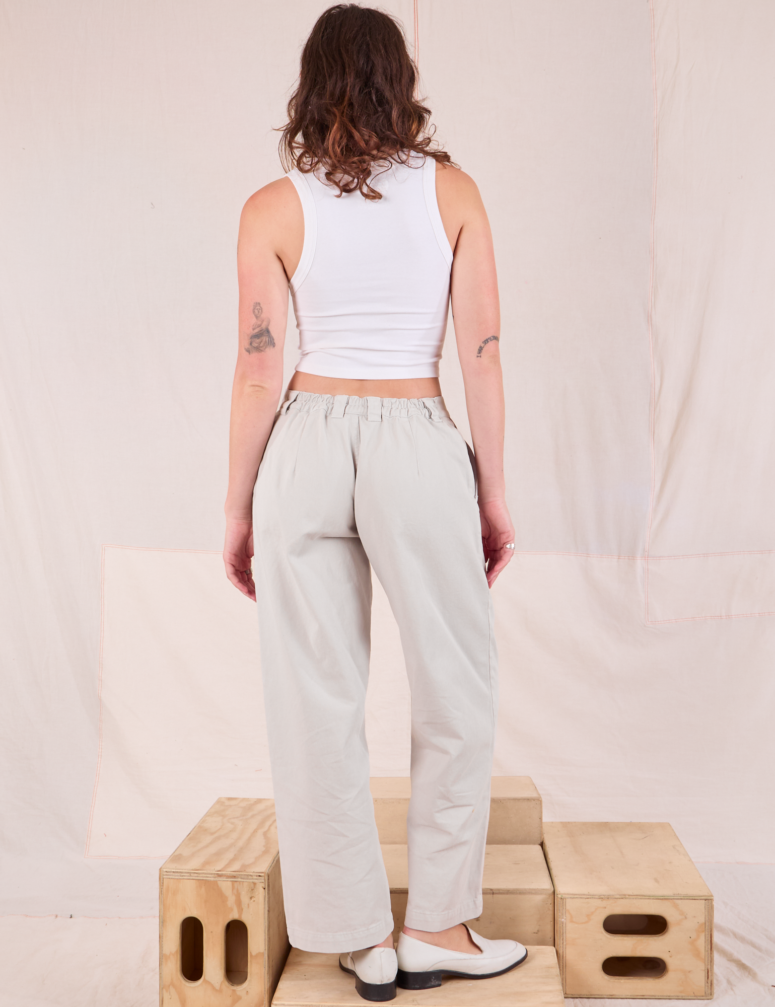 Back view of Mid-Rise Pleated Trousers in Stone White and Cropped Tank in vintage tee off-white on Alex