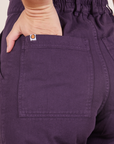 Back pocket close up of Short Sleeve Jumpsuit in Nebula Purple. Alex has her hand in the pocket.