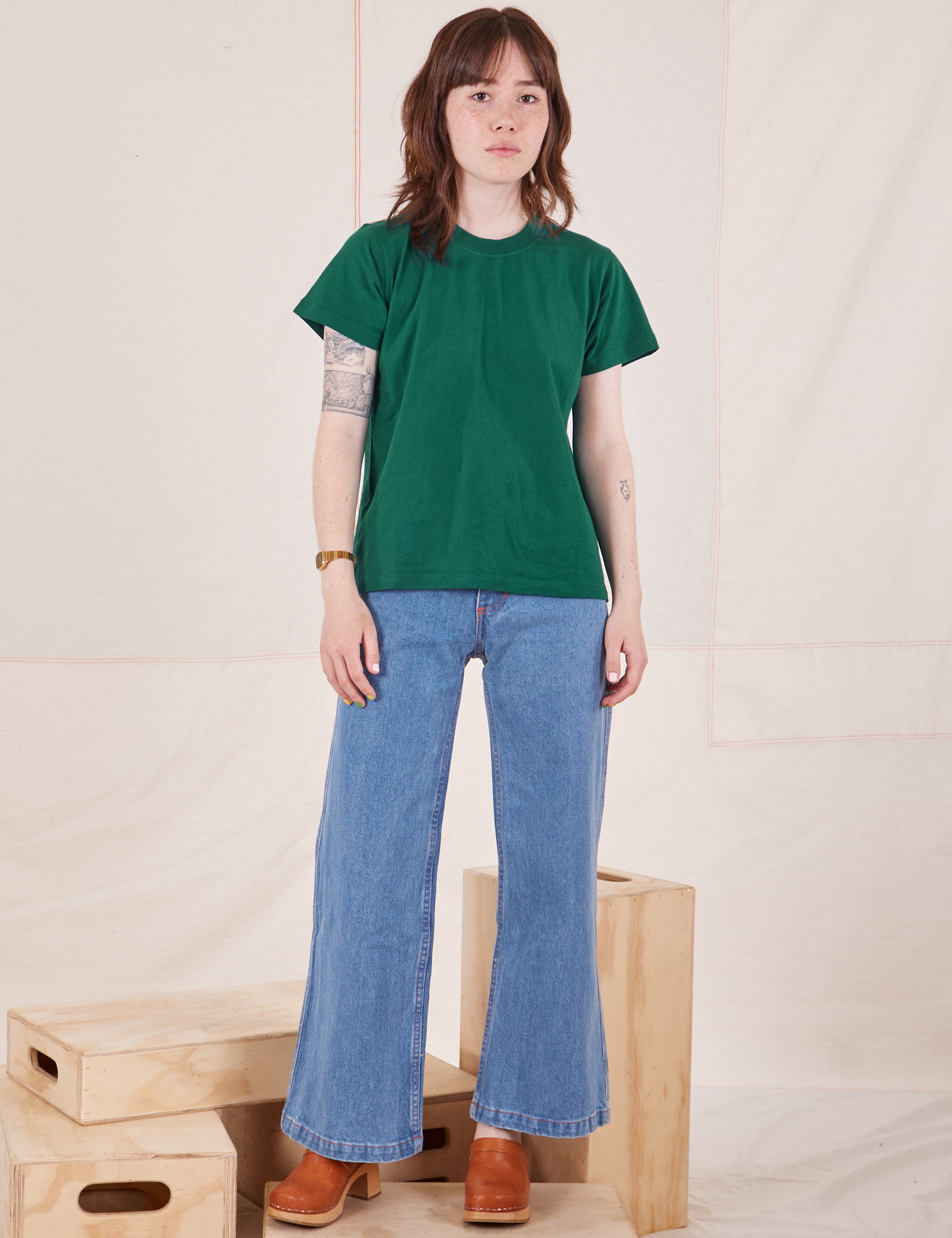 Hana is wearing size P Organic Vintage Tee in Hunter Green paired with light wash Sailor Jeans