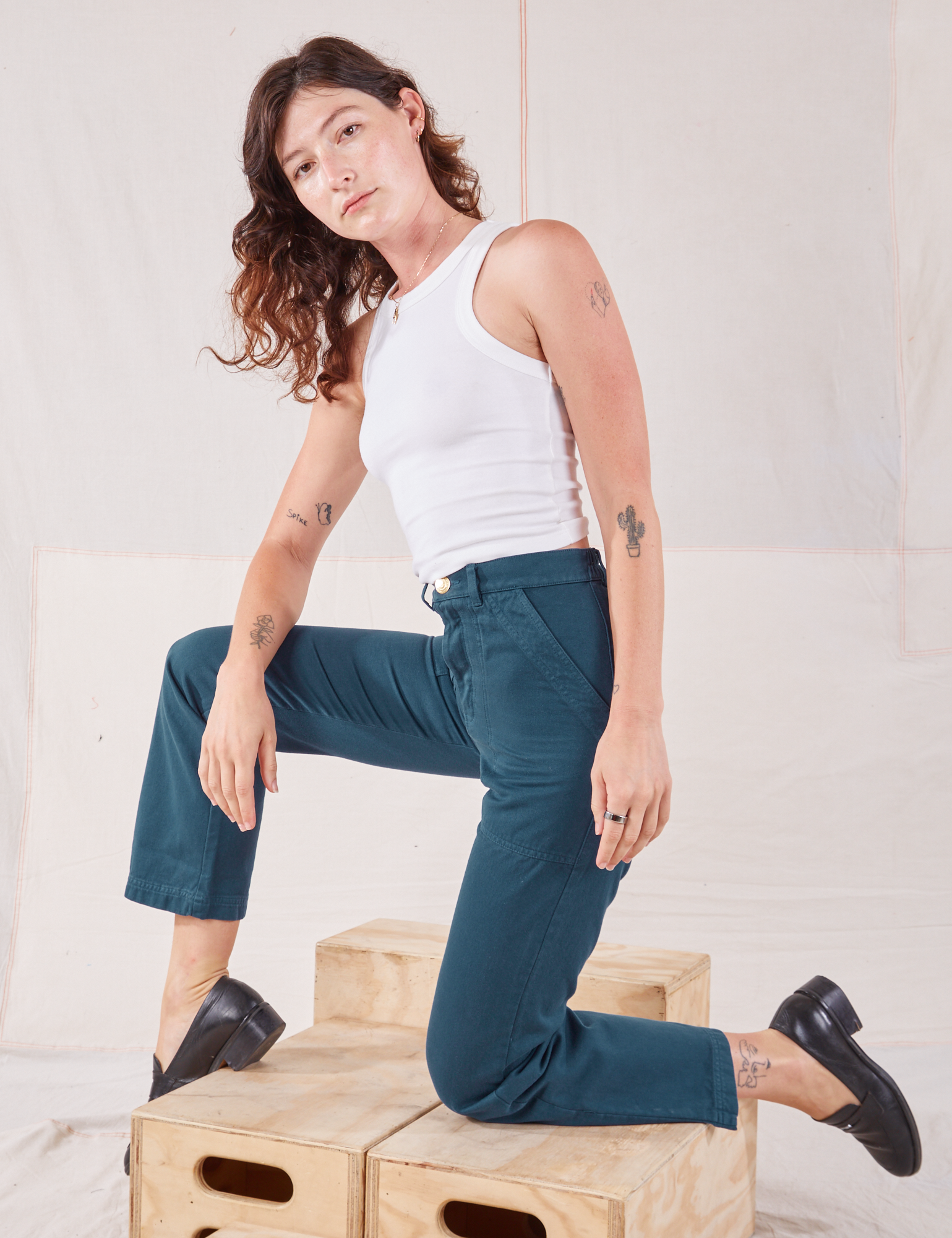 Alex is wearing Organic Work Pants in Lagoon and Racerback Tank in vintage tee off-white