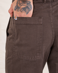 Pencil Pants in Espresso Brown back pocket close up. Jesse has their hand in the pocket.