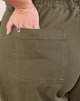 Petite Short Sleeve Jumpsuit in Surplus Green back pocket close up. Ari has her hand in the pocket.