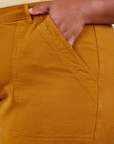 Front pocket close up of Work Pants in Spicy Mustard. Worn by Morgan with her hand in the pocket