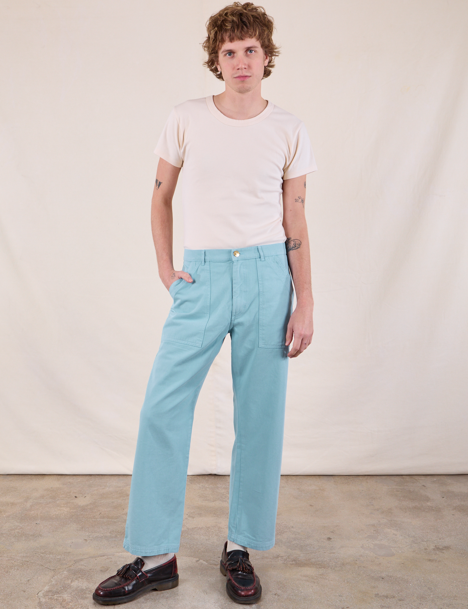 Quinn is 6’4” and wearing M Work Pants in Baby Blue paired with a Burly Tee in Vintage Tee Off-White