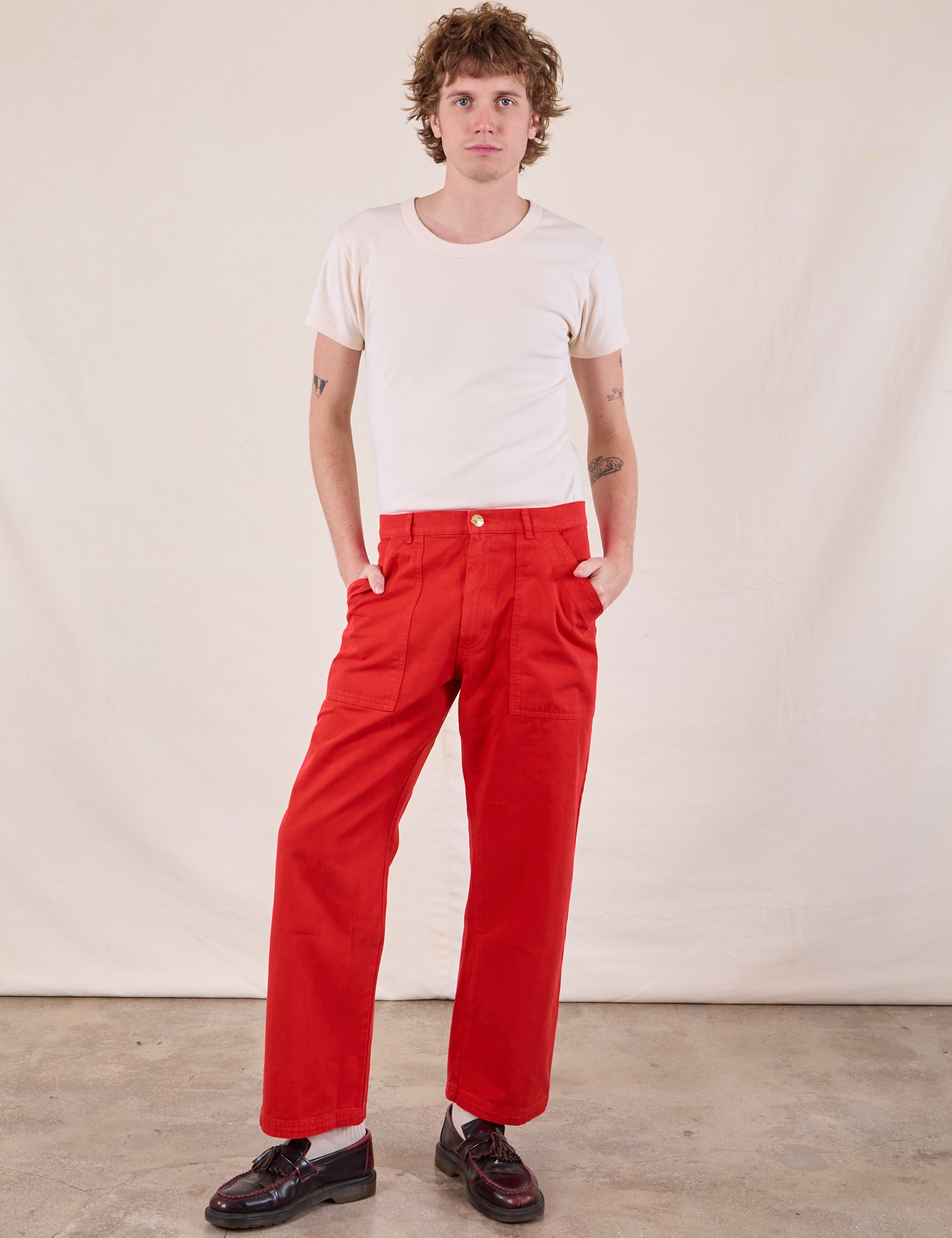 Quinn is 6’4” and wearing M Work Pants in Mustang Red and Burly Tee in Vintage Tee Off-White