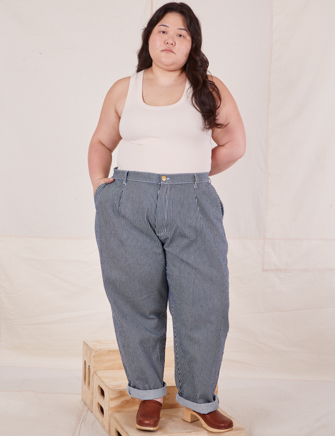 Ashley is 5'7" and wearing 1XL Denim Trouser Jeans in Railroad Stripe paired with a vintage off-white Tank Top