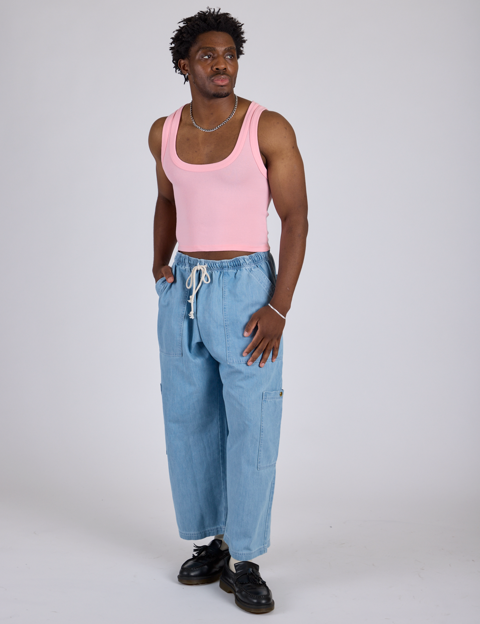 Isaac is wearing Cropped Tank Top in Baby Pink and light wash Denim Drop Pocket Pants